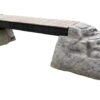 Ellie's Boulder Bridge Pro features a wooden bridge supported by two large gray rock-like structures and bumper pads. Ideal for any dog park or training area, it adds challenge and excitement to outdoor spaces.